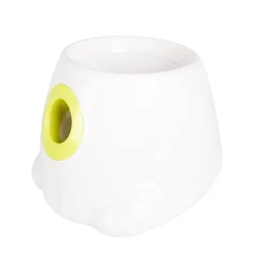 Dog playing with the automatic ball launcher in a park.