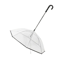 Transparent dog umbrella with built-in leash and black curved handle.