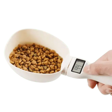 Electronic measuring spoon for pet food, shown with dog kibble